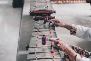 una mano de hombre usa batik jugando género gamelan o slenthem. foto