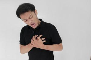 ataque al corazón o corazón roto de un joven asiático con una emoción herida que usa camisa negra foto