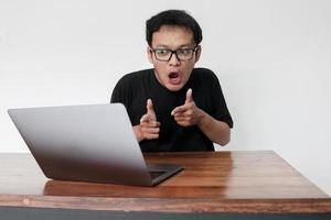 Wow face of Young Asian man shocked what he see in the laptop when working isolated grey background photo