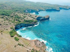 Aerial drone top view of coral beach and blue ocean waves In Nusa Penida, Bali, Indonesia. Overhead View Of Rocky Coast And Coves photo