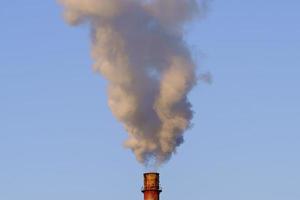 White thick smoke from the boiler room chimney. Smoke against the blue sky. photo