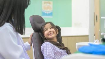 una niña linda con los dientes examinados por un dentista en una clínica dental, revisión de dientes y concepto de dientes sanos foto