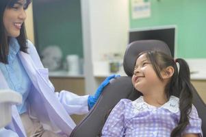 una niña linda con los dientes examinados por un dentista en una clínica dental, un chequeo dental y un concepto de dientes sanos foto