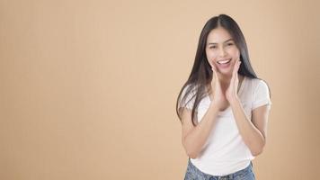 un retrato de una mujer asiática con una camiseta blanca sobre un estudio de fondo marrón claro foto