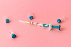 Syringe with several medical vials for injecting on pink background. photo