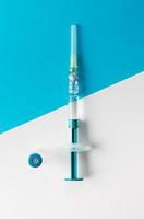 Syringe with medical vial for injection on blue and white background. Top view. photo