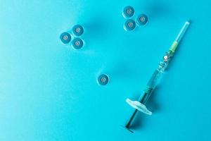 Syringe with several medical vials for injection on blue background. Top view. photo