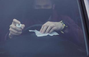 man in protective mask disinfects the car photo