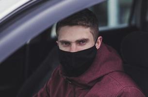 a man driving a car in black protective mask photo