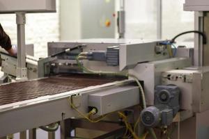 línea para la producción de chocolate en una fábrica industrial. proceso automático en la línea de producción de dulces. imágenes de la fábrica de chocolate durante la producción. cinta transportadora con dulces. foto