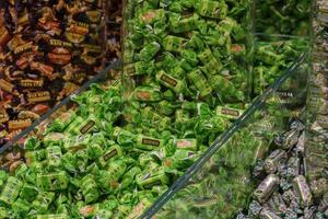 Lots of sweet bright chocolates named Kara-kum, nougat, chamomile on the Roshen shop window. Confectionery, shop. Sweet food texture background. Ukraine, Kiev - February 09, 2022. photo