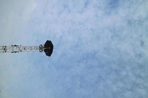 a high lamppost under a bright cloud photo