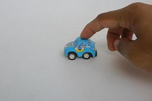 hand touching small blue toy car on a white background photo