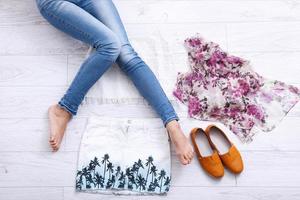 Stylish outfit with accessories and female legs on white wooden background. Top view and copy space photo