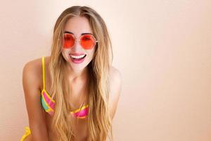 Close Up Of Happy Girl in pink sunglasses isolated. Summer holidays and fun time weekend. Summertime concept. Smiling young woman in fashion swimsuit. Selective focus. Beach Summer outfit. Copy Space photo