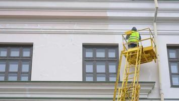 Painters standing on Aerial ladder paint the wall on construction site photo