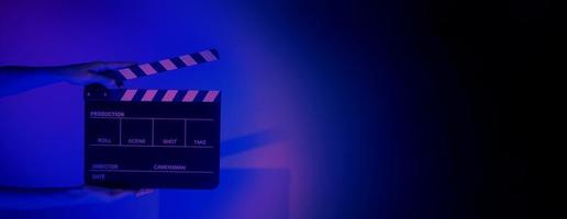 Hand holds empty film making clapperboard on color background in studio photo