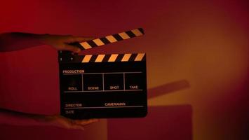 Hand holds empty film making clapperboard on color background in studio photo