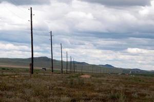 Landscape in central Mongolia close to the main road. Electricity poles along the roal. Green hills in the background. photo