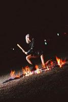 Portrait of stylish blonde grunge young woman  with the club near the fire at night photo