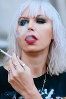 Portrait of stylish blonde grunge young woman with make up smoking cigarette photo