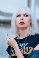 Portrait of stylish blonde grunge young woman with make up smoking cigarette photo