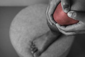 The man holds his pain point of knee joint. The red point shows position of Injury. Black and white color. photo