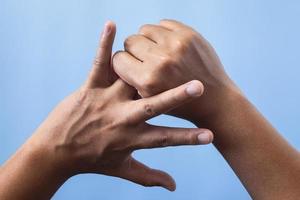 Office syndrome concept. Ring finger is massaged and stretched after working. Close up shot isolate on blue background. Backhand view. photo