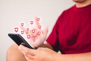 concepto de día de san valentín. el hombre usa el signo de la mano para dar amor a través de un teléfono inteligente. efecto visual en forma de corazón. foto