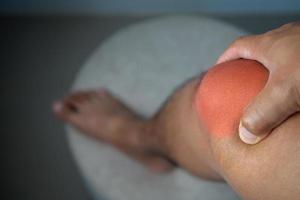 The man holds his pain point of knee joint. The red point shows position of Injury. photo