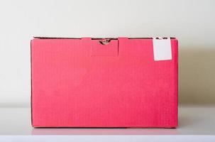 Pink cardboard box on a white table and a light background. photo