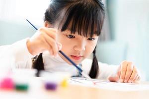 retrato de una niña sentada y pintando en casa foto