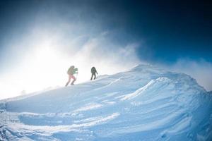 escaladores suben a la cima de la montaña en invierno foto