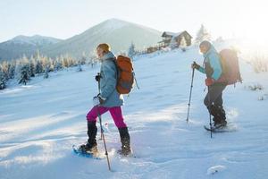 Two women walk in snowshoes in the winter trekking photo