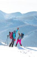 two women climbed to the top of the mountain during a winter hike, girl gives high five to friend photo