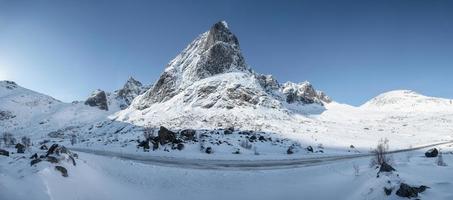 Panorama of snowy mountain range with blue sky and highway in Nordland photo