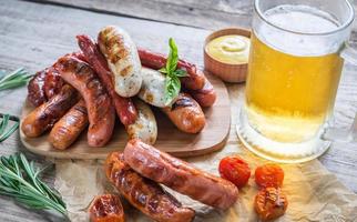 salchichas a la parrilla con un vaso de cerveza foto