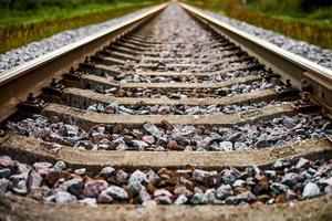 Railway track line going into distance, railroad train track with crushed stone, two parallel rails photo