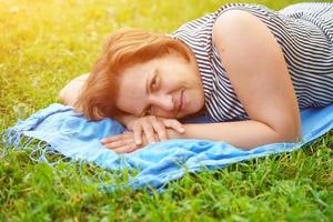 Cute happy woman lying on the green grass resting photo