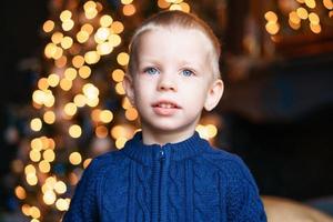 niño de retrato en las noches de invierno contra las luces de Navidad de fondo. entusiasmado foto