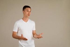 man in a white T-shirt gestures against the background photo