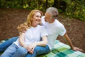 Adult couple in the park on a blanket hugging photo