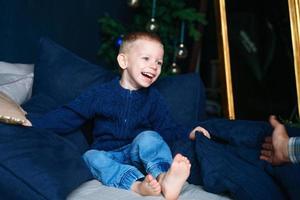 Cute little blond toddler boy in blue sweater is having fun and playing photo