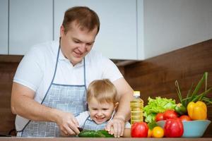 Dad and son preparing a salad in the kitchen , the concept of family cooking