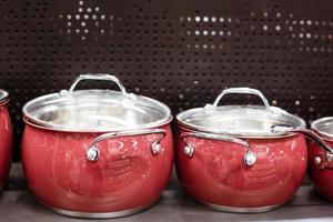 Beautiful red new pans stand on a shelf in a store photo