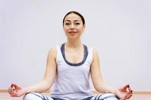 Happy woman doing yoga at home against wall background photo