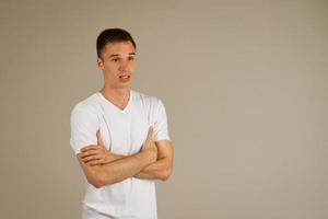 man in a white T-shirt gestures against the background photo