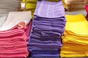 toallas multicolores apiladas en la estantería de la tienda, foto