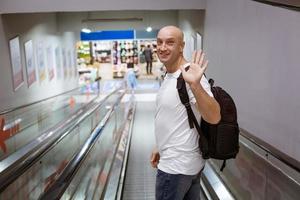 Bald man walking down the escalator with a backpack photo