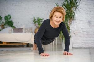 Mature woman doing push-UPS at home, healthy lifestyle concept